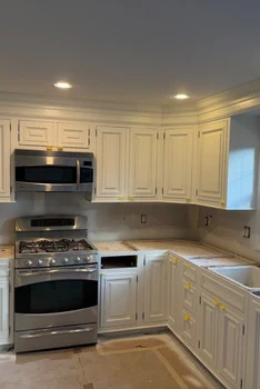 Kitchen cabinetry finishing in progress with masked surfaces