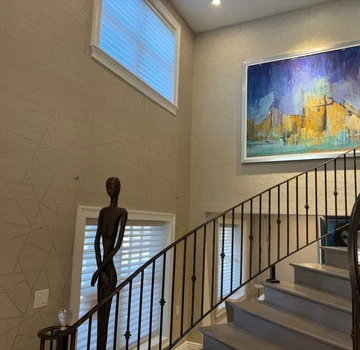 Two-story stairwell with textured plaster walls and iron railing
