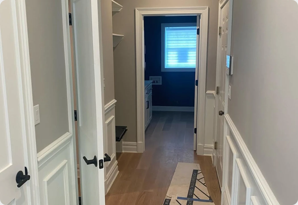Hallway with painted wainscoting and navy interior door